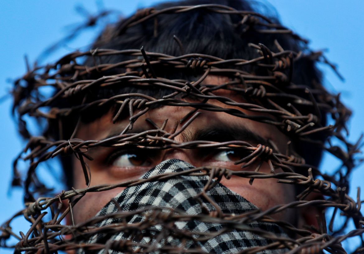 A masked Kashmiri man with his head covered with barbed wire attends a protest after Friday prayers during restrictions following the scrapping of the special constitutional status for Kashmir by the