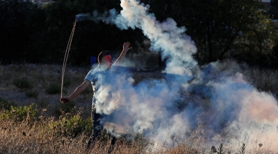 A Palestinian demonstrator returns a tear gas canister during a protest against Israel's plan to annex parts of the Israeli-occupied West Bank, near the Jewish settlement of Beit El near Ramallah July