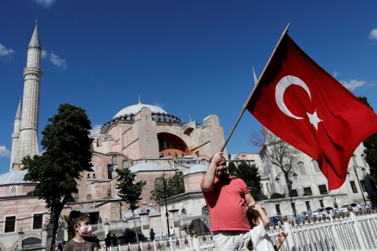 A man waves a Turkish Flag in front of the Hagia Sophia or Ayasofya, after a court decision that paves the way for it to be converted from a museum back into a mosque, in Istanbul
