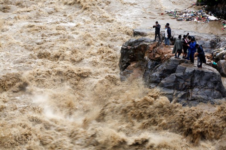 Nepalese people takes photos on the banks of flooded Bagmati river in Kathmandu, Nepal, Tuesday, July 21, 2020. Landslides and flooding caused by continuous heavy rainfall has blocked the main highway