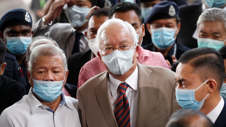 Former Malaysian Prime Minister Najib Razak, center, wearing a face mask prays with his supporters upon arrival at court house in Kuala Lumpur, Malaysia, Tuesday, July 28, 2020. Malaysian High Court t