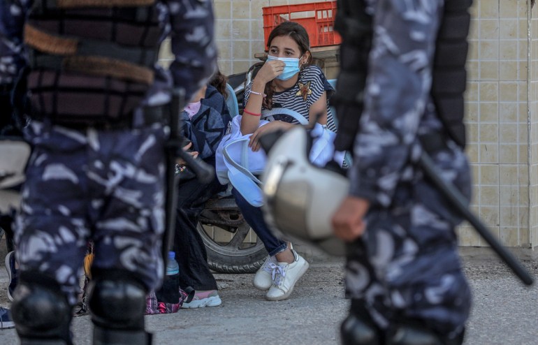 epa08596842 A Palestinian girl waits with her family to cross into Egypt through the Rafah border crossing between Gaza Strip and Egypt after five months of closure as a precautionary measure against
