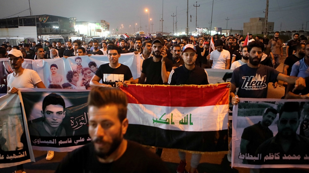 demonstrators hold national flags and posters of protesters who were killed during previous demonstrations, in Basra, Iraq.