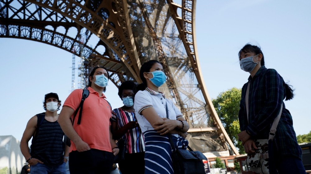 Visitors wearing protective facemasks queue as they wait for the partial reopening of Eiffel Tower on June 25, 2020, in Paris, as France eases lockdown measures taken to curb the spread 