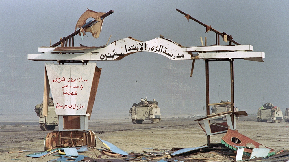 (FILES) In this file photo taken on February 25, 1991, Saudi light armoured vehicles pass by a bombed arch of a school near the coastal city of al-Ahmadi in Kuwait as Allied forces continue to advance