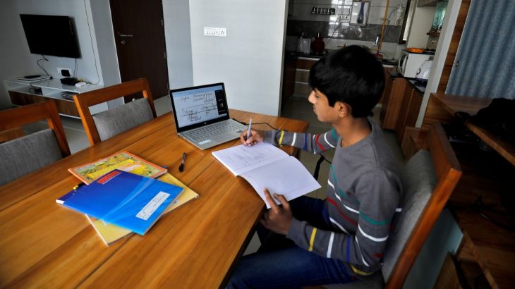 A student makes notes as he attends an online class at his home after Gujarat government ordered the closure of schools and colleges across the state amid coronavirus disease (COVID-19) fears, in Ahme