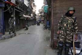 Indian security force personnel stand guard in front closed shops in a street in Srinagar, October 30, 2019 [File: Reuters/Danish Ismail]