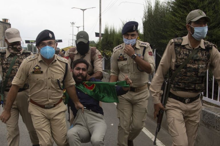 Indian policemen detain a Kashmiri Shiite Muslims as he and others