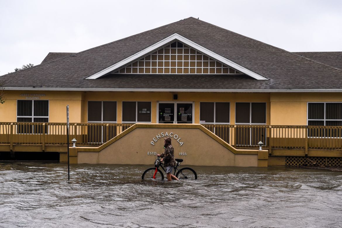 A man walks with his bicycle through a street flooded by rains from Hurricane Sally in downtown Pensacola, Florida on September 16, 2020. - Hurricane Sally barrelled into the US Gulf Coast early Wedne