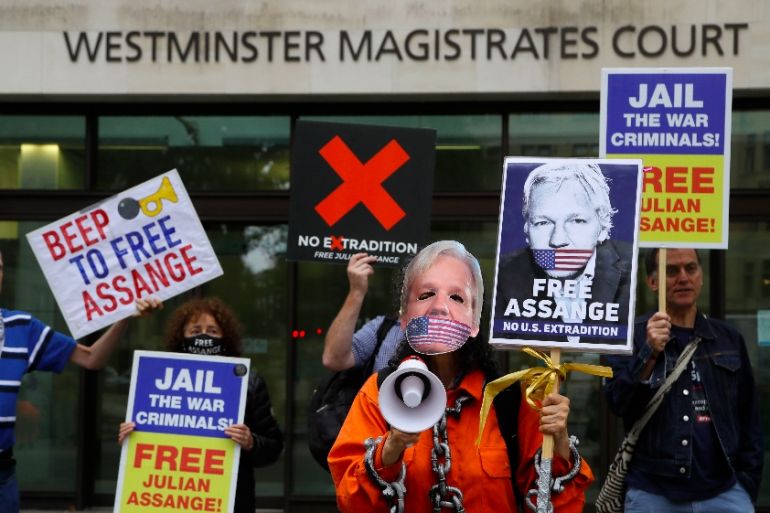 Demonstrators hold banners outside Westminster Magistrates Court in London, Friday, Aug. 14, 2020. A final procedural hearing in the Julian Assange extradition case will take place at the court