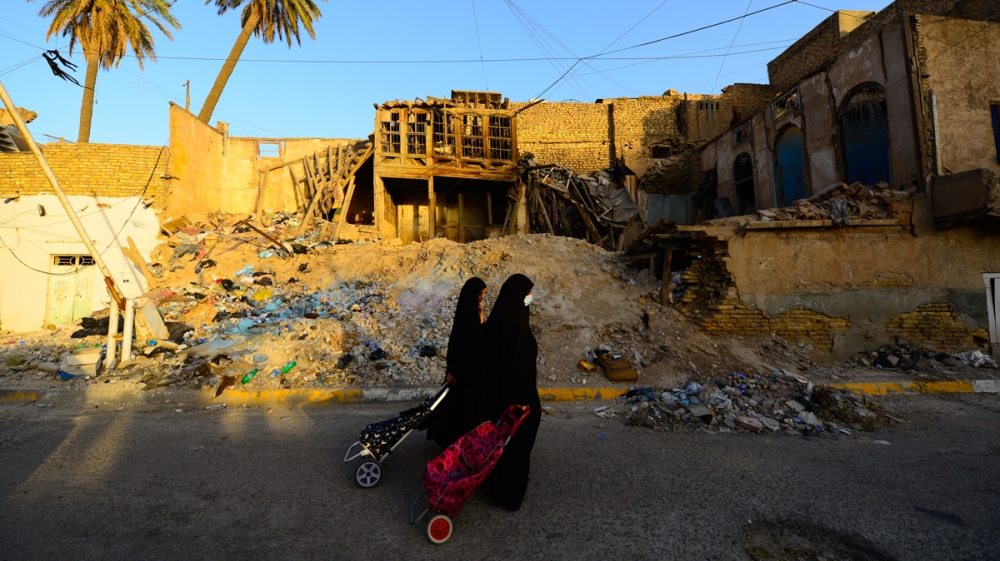 Women walk past a traditional house in Baghdad’s Shewake neighborhood. Many of the buildings have collapsed due to neglect, while others have been demolished to make way for new structures. [Haider Ha