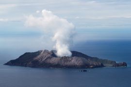 An aerial view of the Whakaari, also known as White Island. There are clouds of smoke rising from the island.