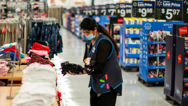 A worker is seen wearing a mask while organizing merchandise at a Walmart store