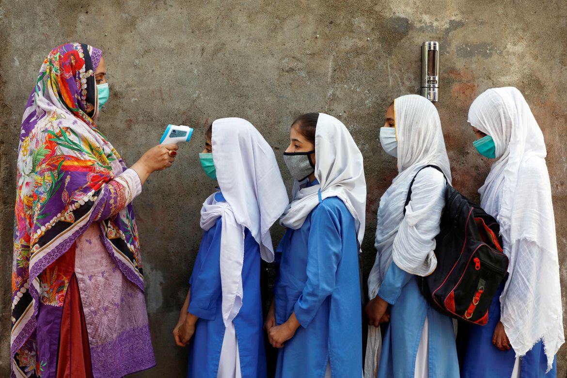 Pakistani students wear protective face masks as they have their temperature checked