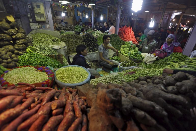 Customers buy vegetables from a stall at a market in Ahmedabad, India