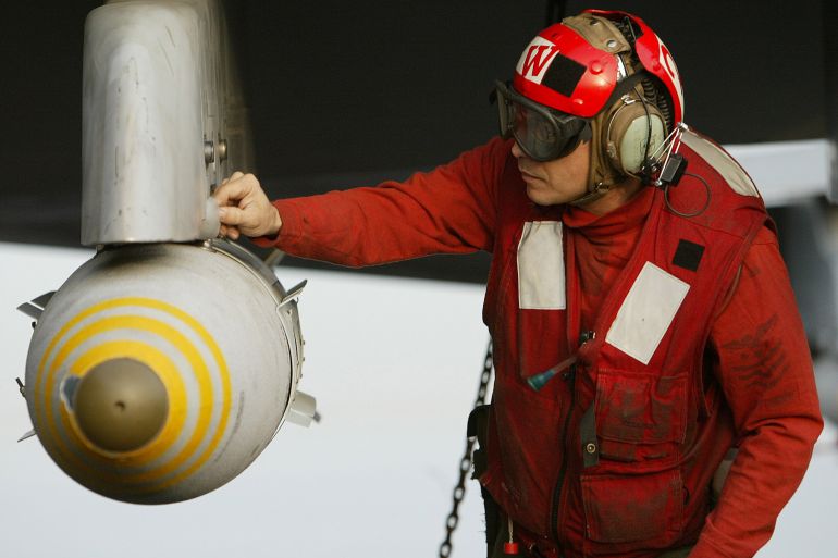 A US aviation ordnanceman makes a final check on a 500-pound JDAM satellite guided bomb on the wing of an F/A-18 Hornet fighter jet