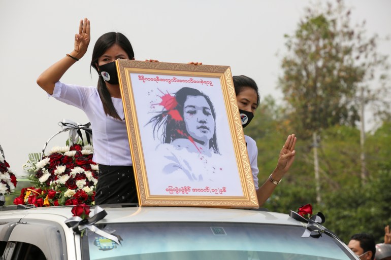 Women in white hold a hand drawn portrait of Mya Thwate Thwate Khaing who was shot in the head by the military during a demonstration in Naypyidaw