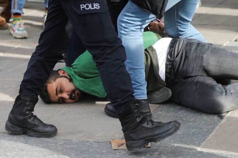 A student demonstrator is being restrained on the ground by a plainclothes officer (unseen)