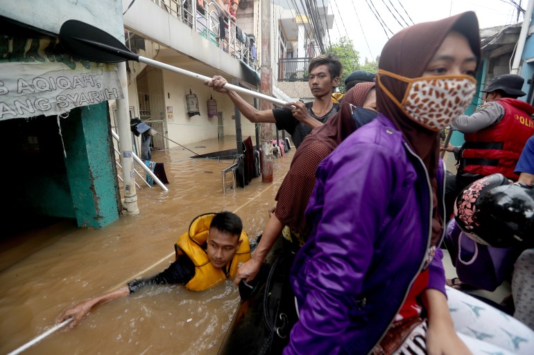 An Indonesian national police officer pushes a rubber boat in a flooded street to rescue residents in Jakarta, Indonesia.