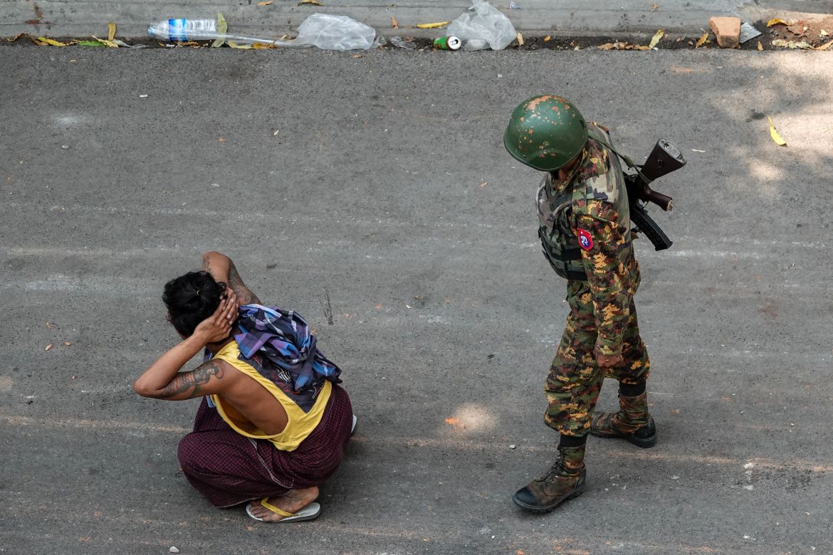 A soldier stands next to a detained man during a demonstration against the military coup in Mandalay on March 3, 2021.