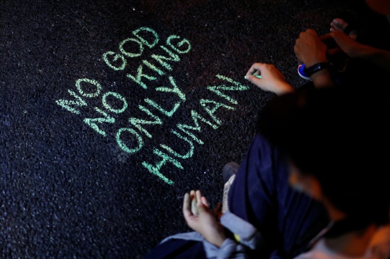 Anti-government demonstrators write a slogan on a street during protest demanding the release of arrested leaders charged with lese majeste law in Bangkok, Thailand March 6, 2021
