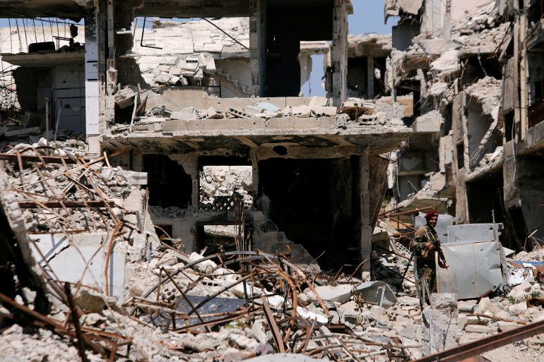 A member of Syrian forces stands guard in front of destroyed buildings in Jobar, eastern Ghouta, in Damascus, Syria, April 2, 2018