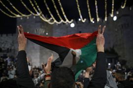 Palestinian protesters wave the national flag outside the Damascus Gate in Jerusalem&#39;s Old City on April 26, 2021 [AFP/Ahmad Gharabli]