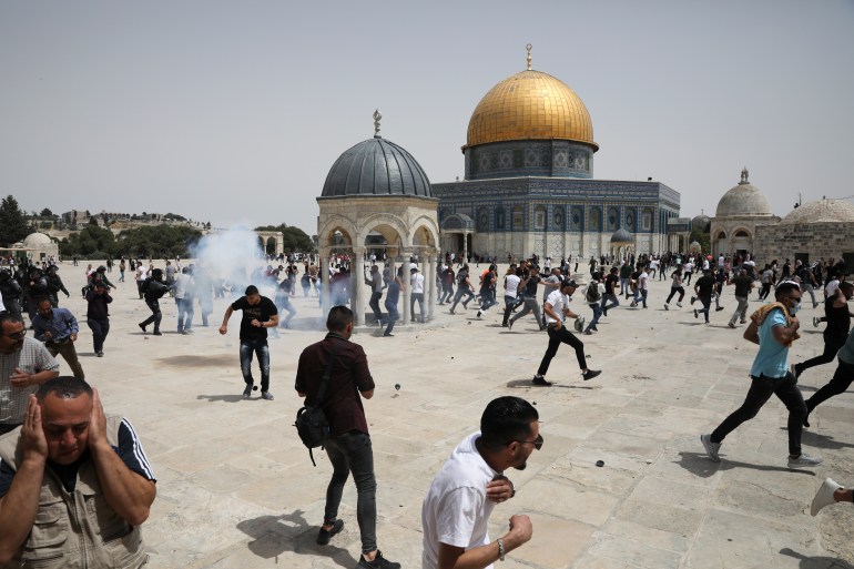 Palestinians run from sound bombs thrown by Israeli police in front of the Dome of the Rock shrine at al-Aqsa mosque complex in Jerusalem, Friday, May 21, 202, as aa cease-fire took effect between Hamas and Israel after 11-day war.