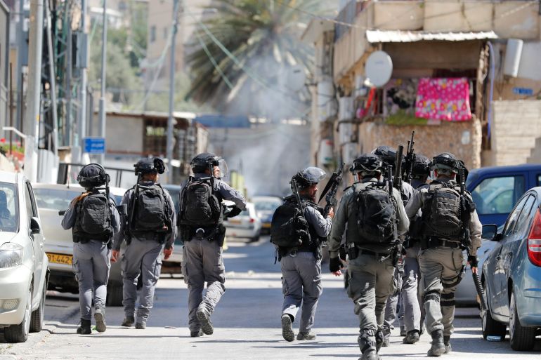 Israeli soldiers walk through a narrow street