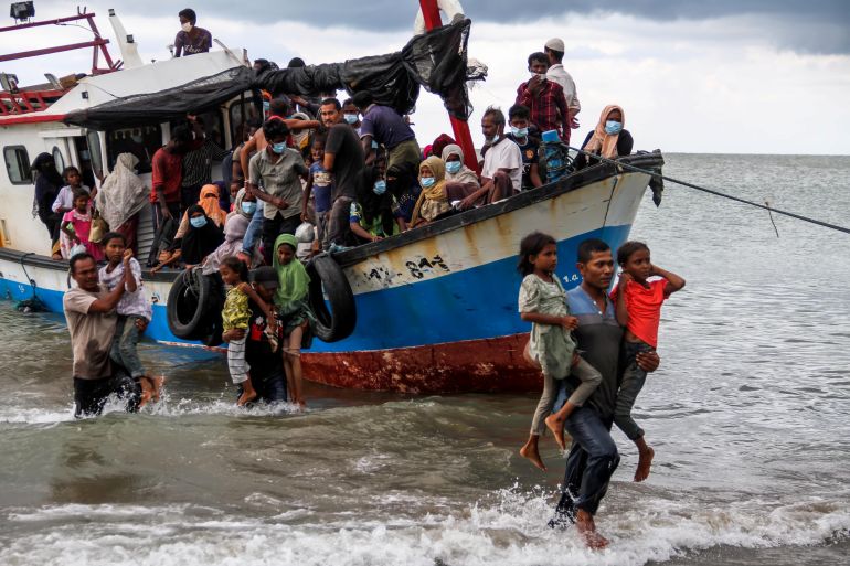 Rohingya refugees are helped ashore by Indonesians after weeks at sea