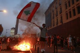 A demonstrator holds the Lebanese flag during a protest near Parliament as Lebanon marks the one-year anniversary of the explosion in Beirut, August 4 [Aziz Taher/Reuters]
