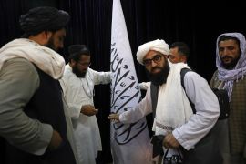 Taliban officials arrange a Taliban flag, before a press conference by Taliban spokesman Zabihullah Mujahid, at the Government Media Information Center, in Kabul, Afghanistan on August 17, 2021 [AP/Rahmat Gul]