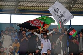 Spectators wave Afghanistan's and Taliban flags