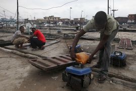 In this photo, a man refuels a small generator on a store rooftop at Oshodi Market in Lagos, Nigeria.