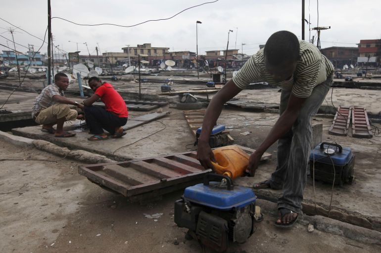 In this photo, a man refuels a small generator on a store rooftop at Oshodi Market in Lagos, Nigeria.