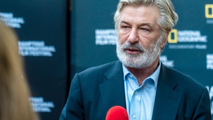 Alec Baldwin in front of a microphone at a film festival.