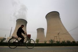 man cycles past China power station