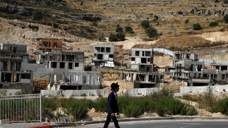 A Jewish settler walks past Israeli settlement construction sites around Givat Zeev and Ramat Givat Zeev in West Bank