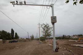 A child plays under police surveillance cameras set up to monitor a dirt road intersection in Kuqa in western Xinjiang province. China on July 16, 2014 [File: Ng Han Guan/AP]