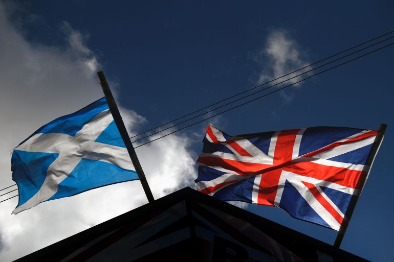 A saltire flag and Union Jack flutter in the wind