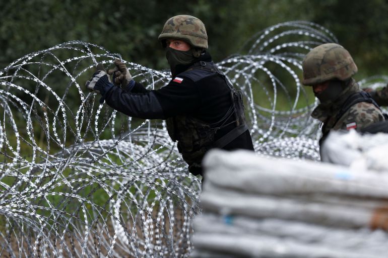 Polish soldiers construct a barbed wire fence on the border with Belarus in Zubrzyca Wielka near Bialystok, eastern Poland on August 26, 2021. - The Polish Ministry of Defence has announced the building of a one hundred kilometer long, two and a half meter high fence along it's border with Belarus after a significant increase in refugee crossings. (Photo by Jaap Arriens / AFP)