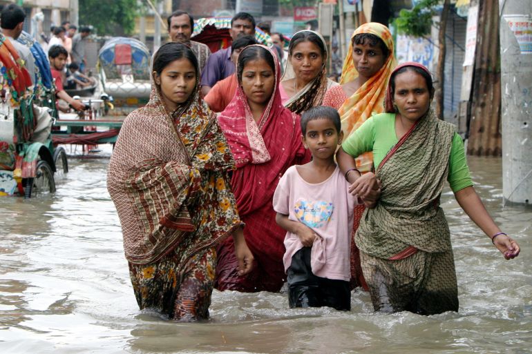 Bangladeshi families wade through a flooded street.