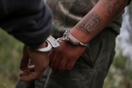A migrant from Central America, is handcuffed by border patrol agents who suspected he was a member of the gang Mara Salvatrucha (commonly known as MS-13) [File: Adrees Latif/Reuters]