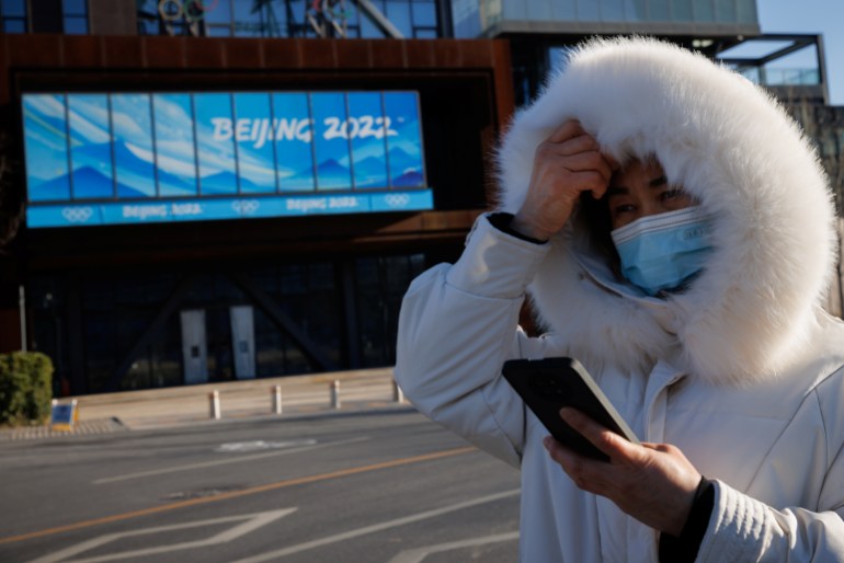 A woman in wearing a face mask stands outside the the headquarters