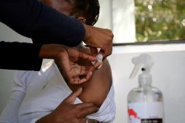 A healthcare worker administers the Johnson & Johnson coronavirus vaccine to a woman in Houghton, Johannesburg, South Africa, on August 20, 2021 [Sumaya Hisham/Reuters]