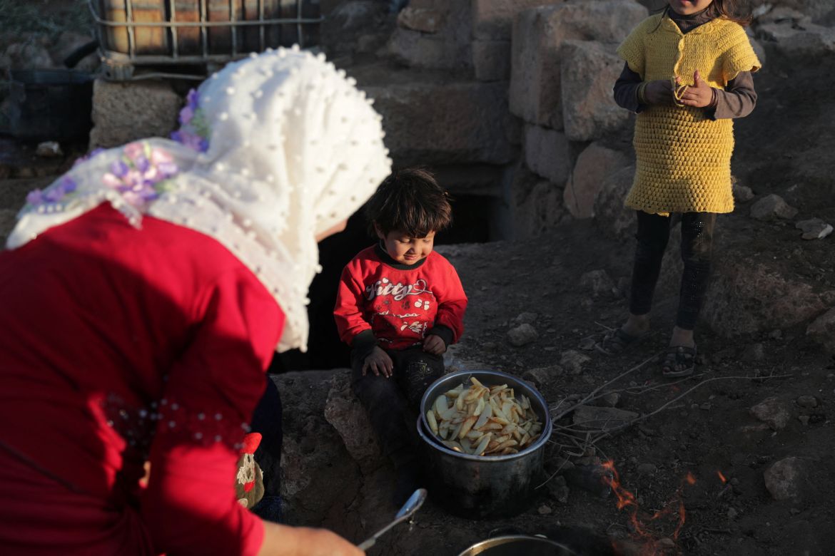 Zahra Abu Khalifa, cooks potatoes with her children at the UNESCO World Heritage Site of Babisqa, Syria