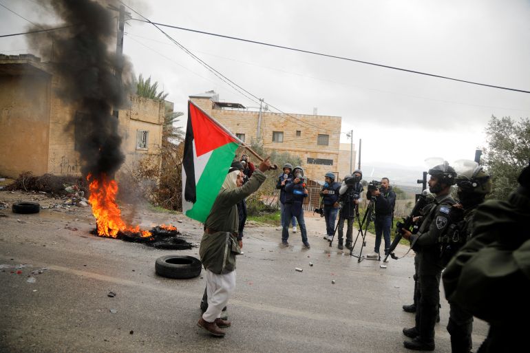 Protesters with Palestinian flag confront Israeli soldiiers near Homesh