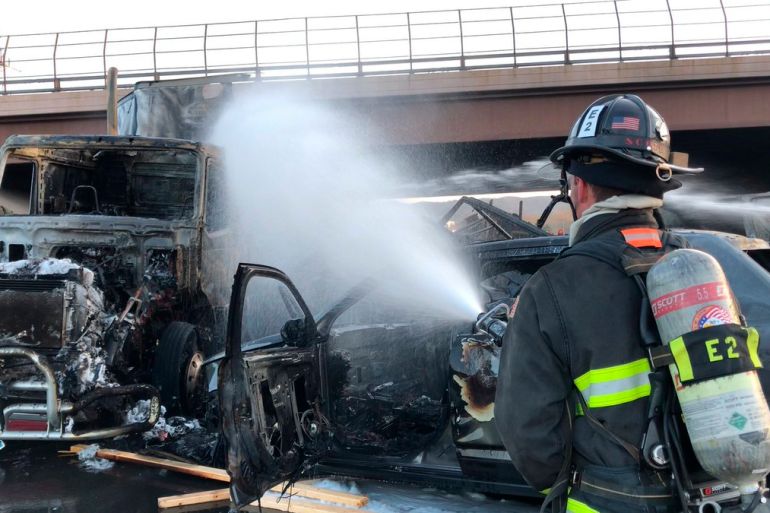 A fireman sprays water on the charred remains of cars and trucks