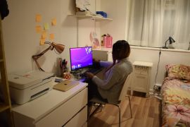 Kiasi Sandrine Mputu sits at a desk in her bedroom