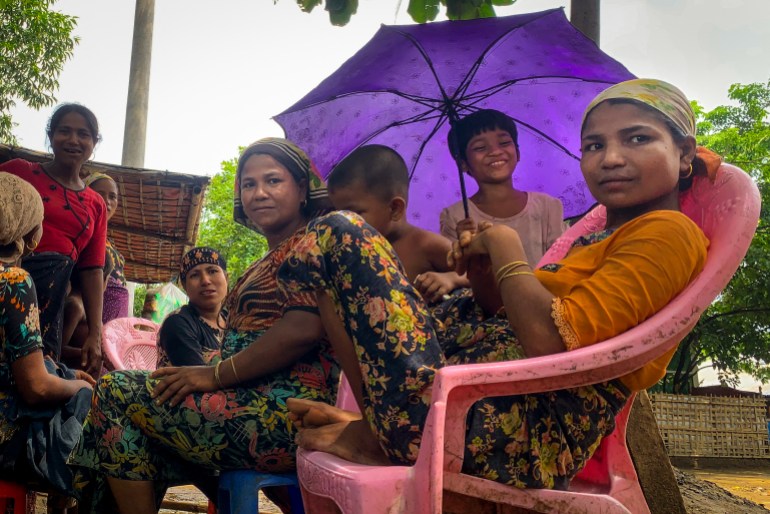 internally displaced Rohingya Muslim women and children gather beneath a purple umbrella in the Thet Kay Pyin camp in Sittwe, Rakhine state